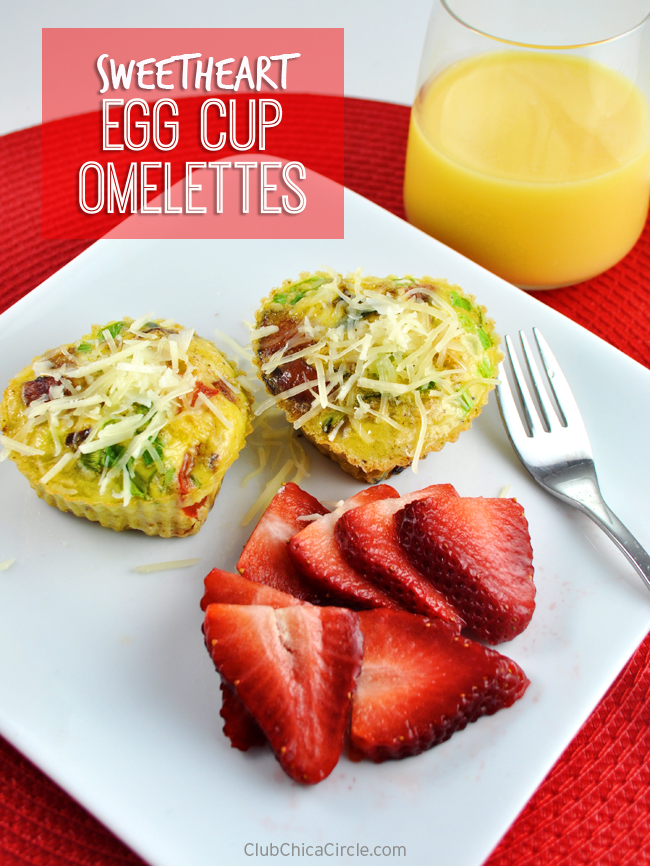 egg cups with cheese on top on a white plate with sliced strawberrie and a glass of orange juice